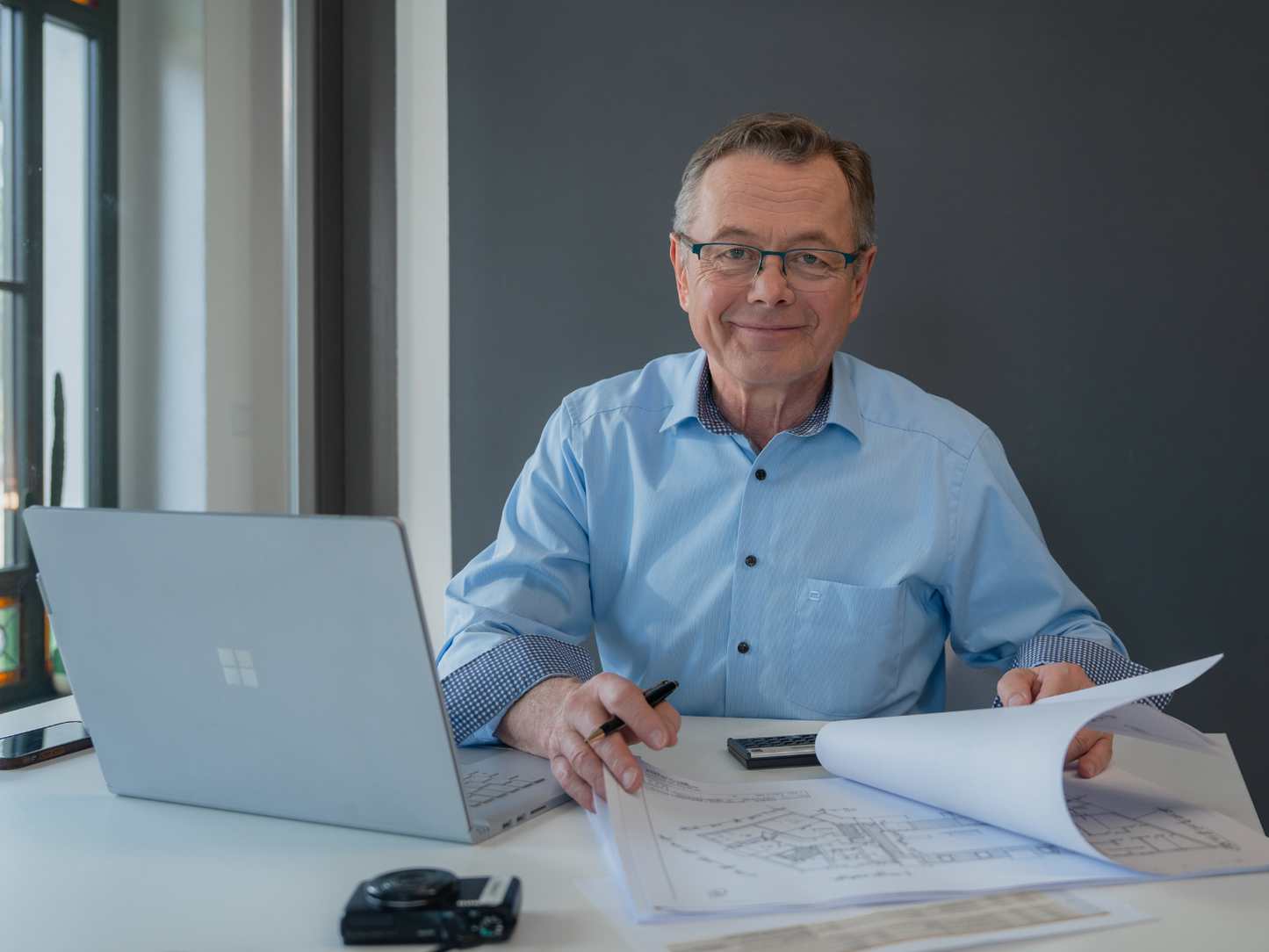 Hans-Jürgen Reppe prüft Grundrisspläne und erstellt ein Immobiliengutachten am Arbeitsplatz.