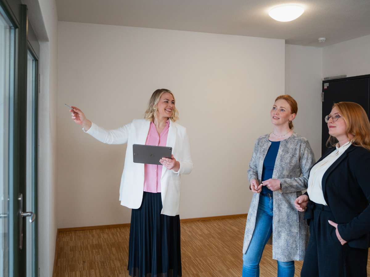 Sachverständige für Immobilienbewertung Christiane Reppe mit Tablet erklärt zwei weiteren Frauen wichtige Aspekte der Immobilie bei der Besichtigung.