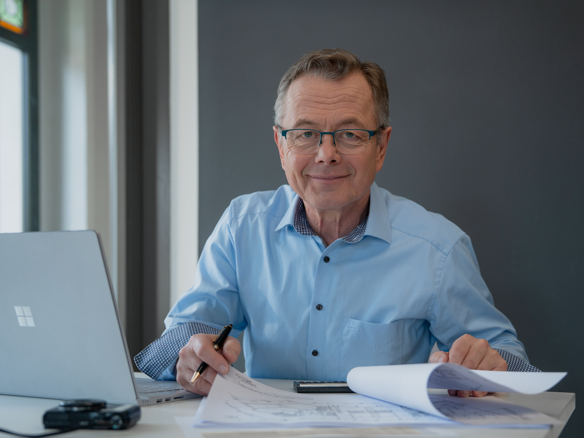 Zertifizierter Immobilienbewerter Hans-Jürgen Reppe am Schreibtisch mit Unterlagen und Laptop