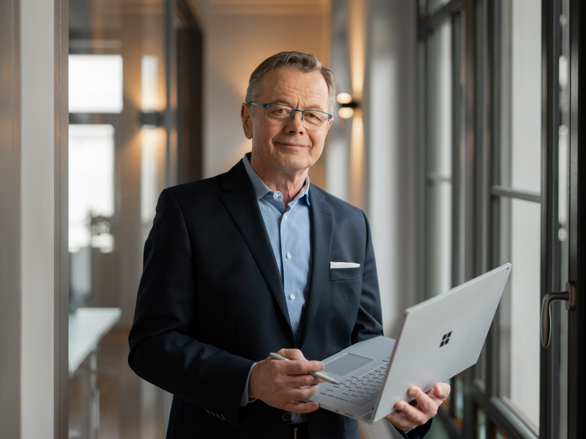 Sachverständiger Hans-Jürgen Reppe arbeitet mit einem Laptop und Stylus an Immobilienunterlagen