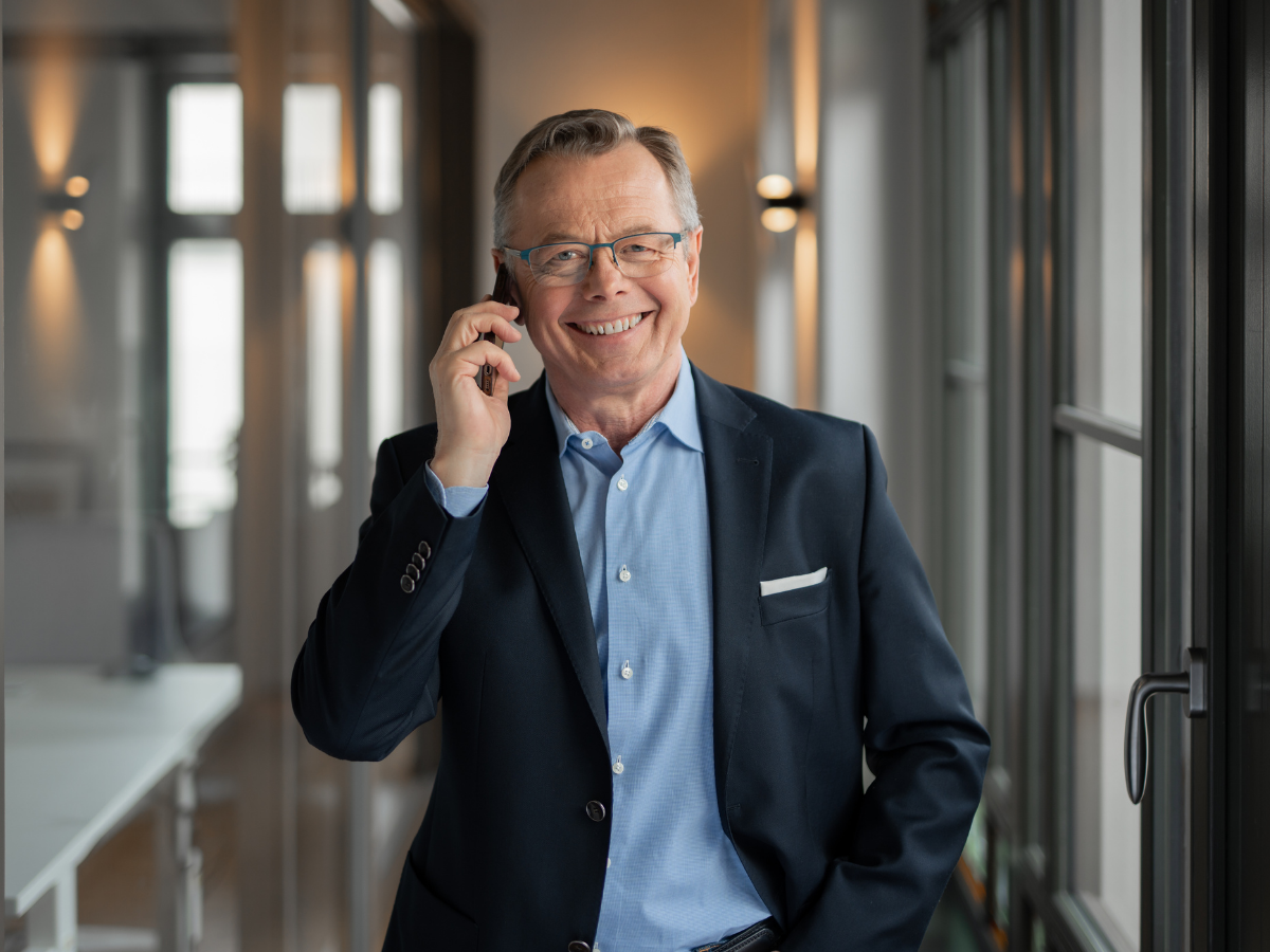 Hans-Jürgen Reppe, zertifizierter Sachverständiger für Immobilienbewertung, im Gespräch am Smartphone im Büroflur
