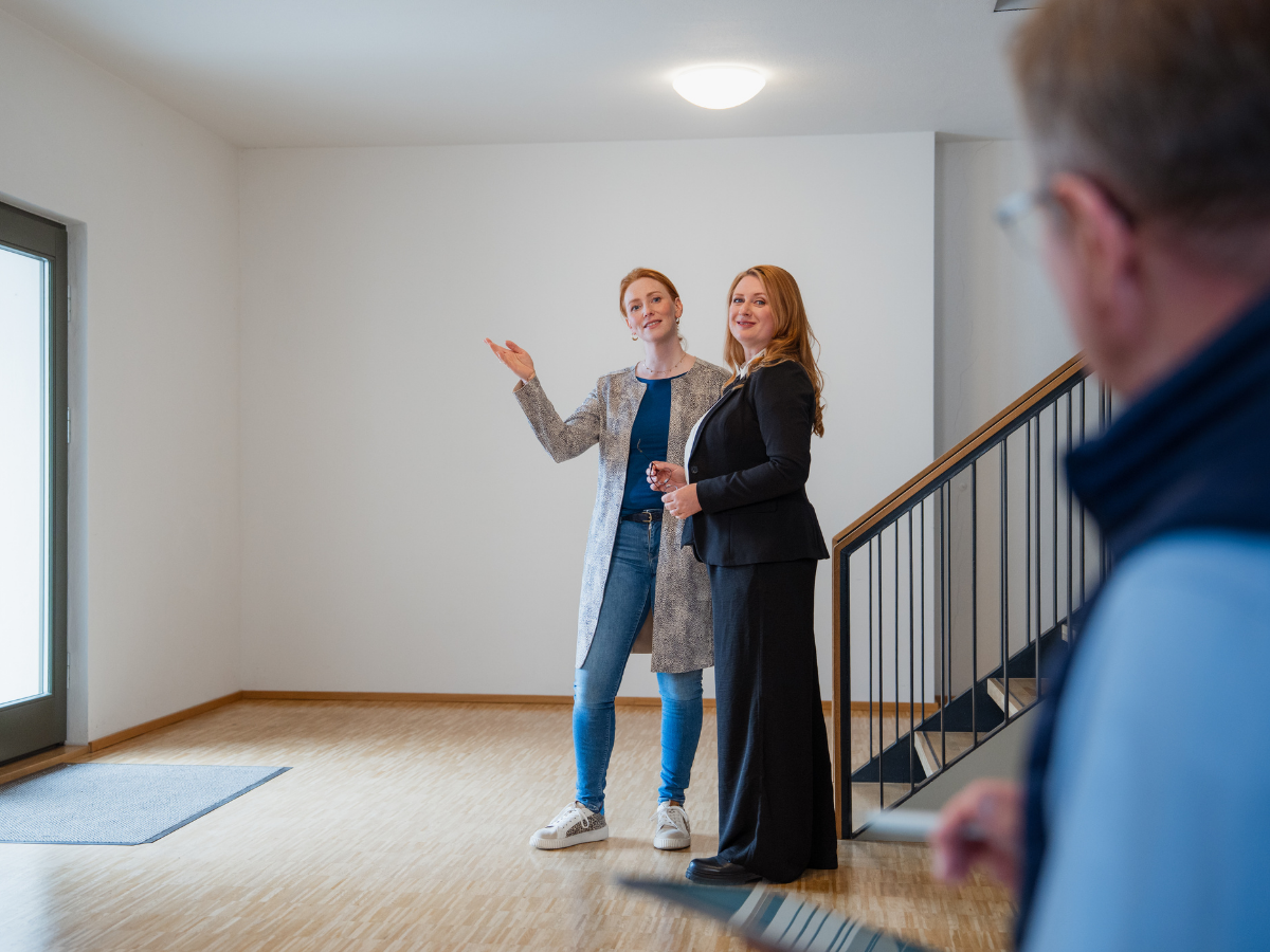 Zwei Auftraggeberinnen präsentieren dem Sachverständigen für Immobilienbewertung Hans-Jürgen Reppe einen Raum während einer professionellen Besichtigung.