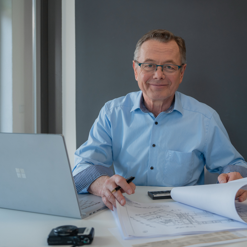 Hans-Jürgen Reppe prüft Grundrisspläne und erstellt ein Immobiliengutachten am Arbeitsplatz.