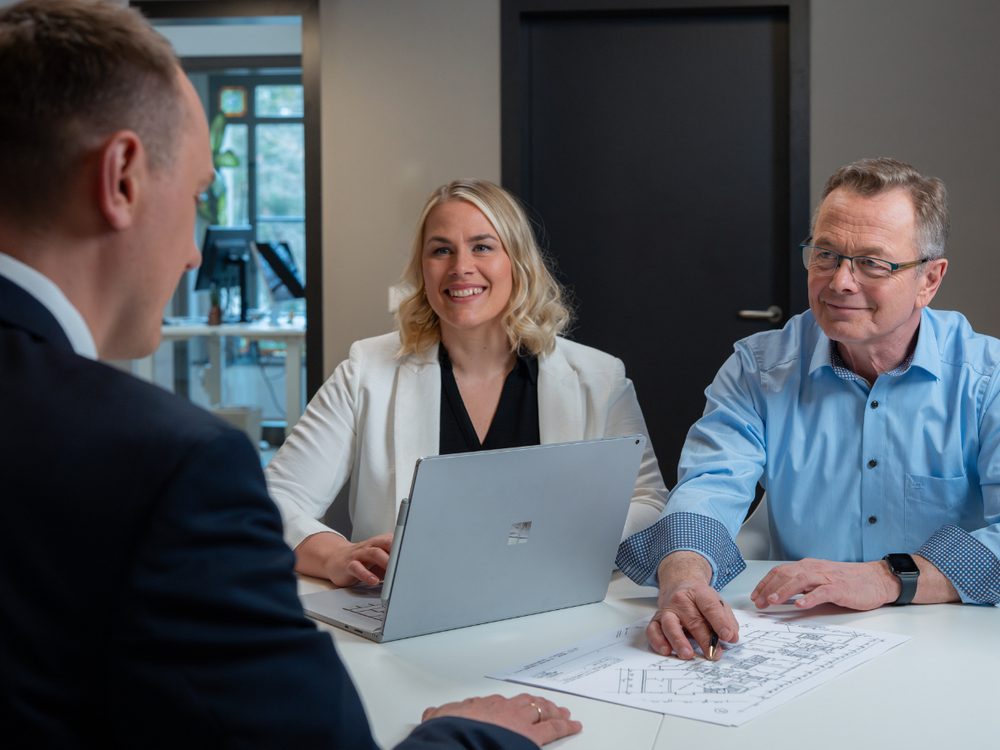 Christiane Reppe und Hans-Jürgen Reppe beraten einen Kunden mit Unterlagen und einem Laptop auf dem Tisch.